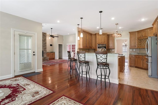 kitchen with brown cabinetry, light stone counters, stainless steel appliances, and a kitchen breakfast bar