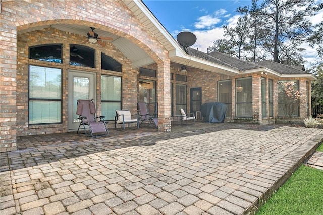 rear view of property featuring ceiling fan, a patio, and brick siding