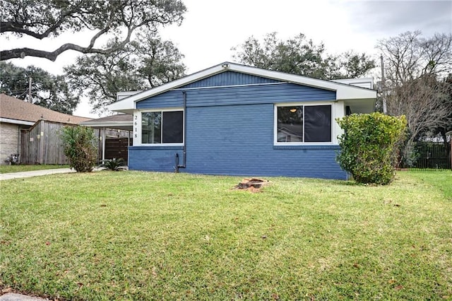 view of front facade featuring fence, a front lawn, an attached carport, and brick siding