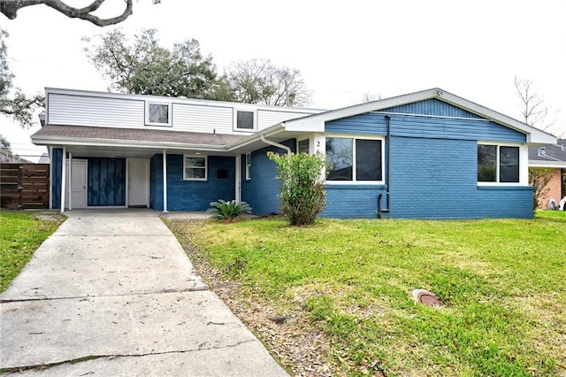 view of front of property featuring driveway, a front lawn, an attached carport, and brick siding