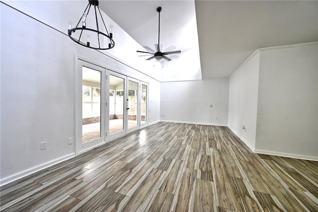 unfurnished living room featuring ceiling fan with notable chandelier, french doors, baseboards, and wood finished floors