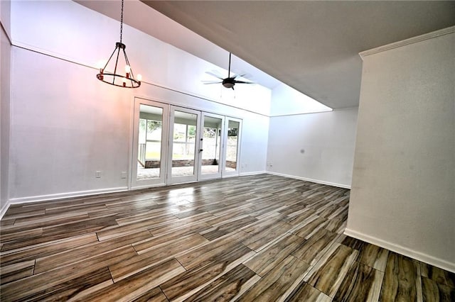 unfurnished living room featuring french doors, dark wood-type flooring, vaulted ceiling, baseboards, and ceiling fan with notable chandelier