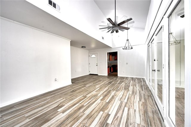 empty room featuring visible vents, wood finished floors, a ceiling fan, and baseboards