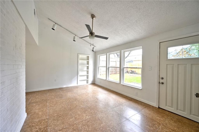 interior space with brick wall, ceiling fan, a textured ceiling, and rail lighting