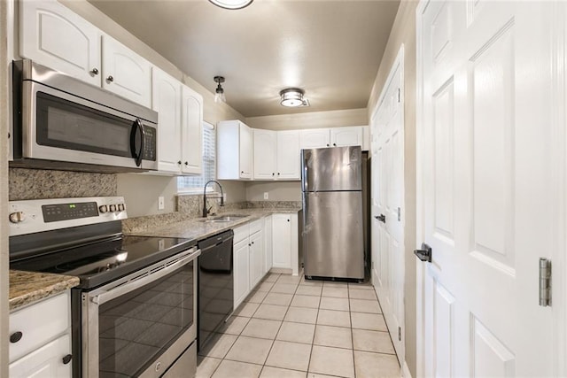 kitchen with light stone counters, appliances with stainless steel finishes, a sink, and white cabinetry