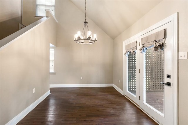 unfurnished dining area featuring vaulted ceiling, dark wood-style flooring, a notable chandelier, and baseboards