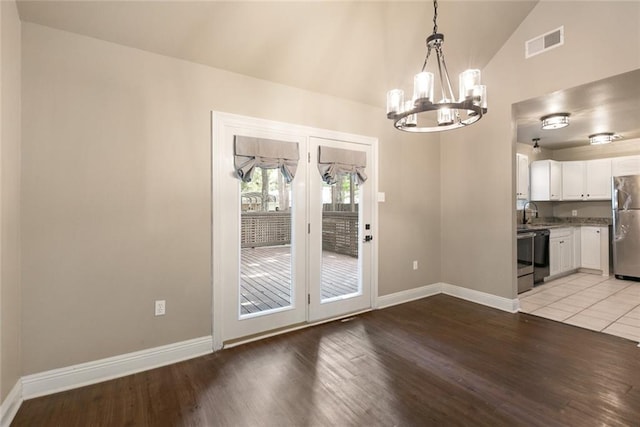 unfurnished dining area featuring baseboards, visible vents, vaulted ceiling, light wood-style floors, and a chandelier