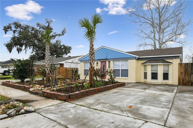 single story home featuring concrete driveway, brick siding, and fence