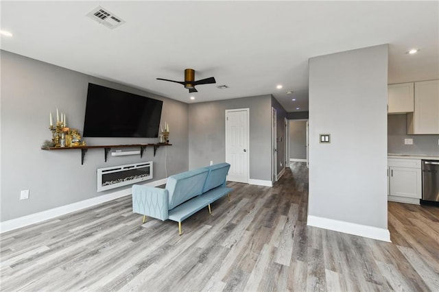 living room featuring light wood-style floors, recessed lighting, visible vents, and baseboards