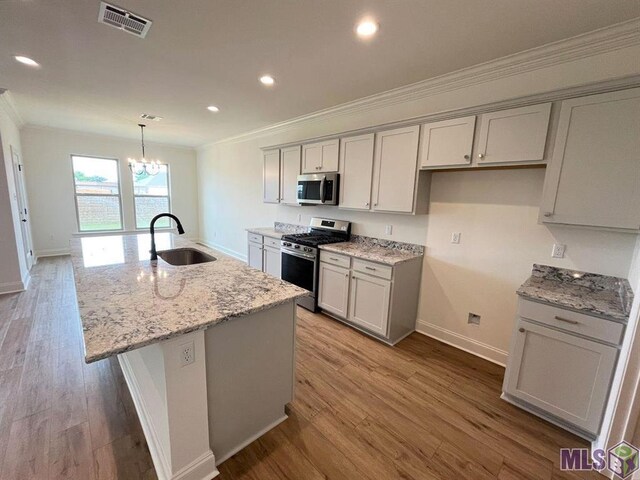 kitchen featuring appliances with stainless steel finishes, a sink, ornamental molding, gray cabinets, and wood finished floors
