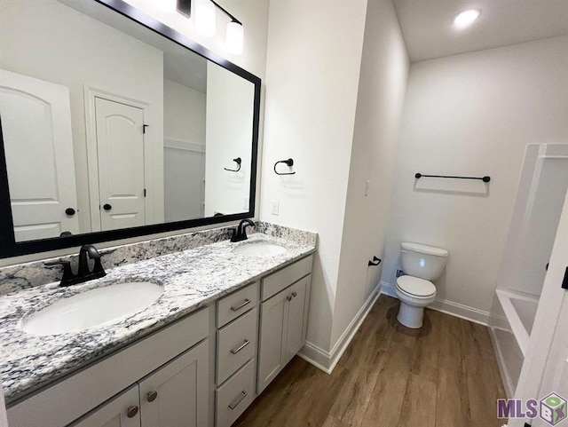 full bath with wood finished floors, toilet, double vanity, and baseboards