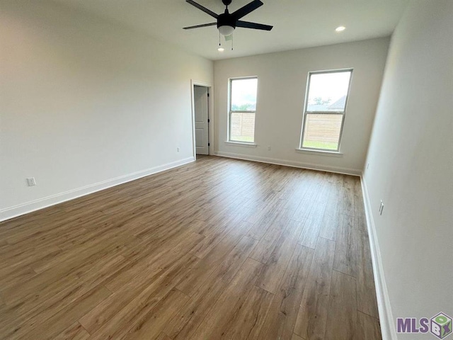 spare room with wood finished floors, a ceiling fan, baseboards, and recessed lighting