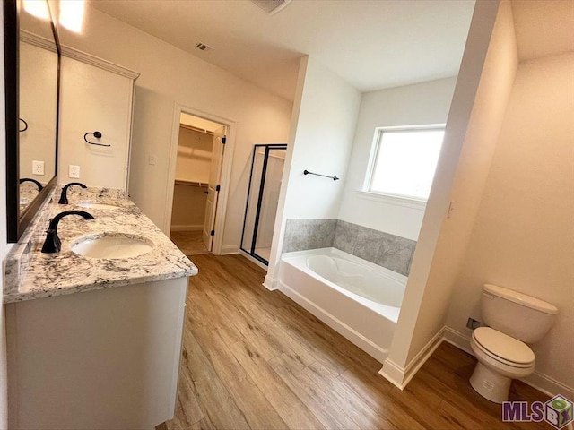 full bathroom featuring wood finished floors, a garden tub, a shower stall, and double vanity