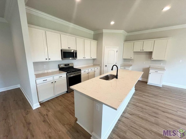 kitchen with appliances with stainless steel finishes, a sink, ornamental molding, white cabinets, and baseboards