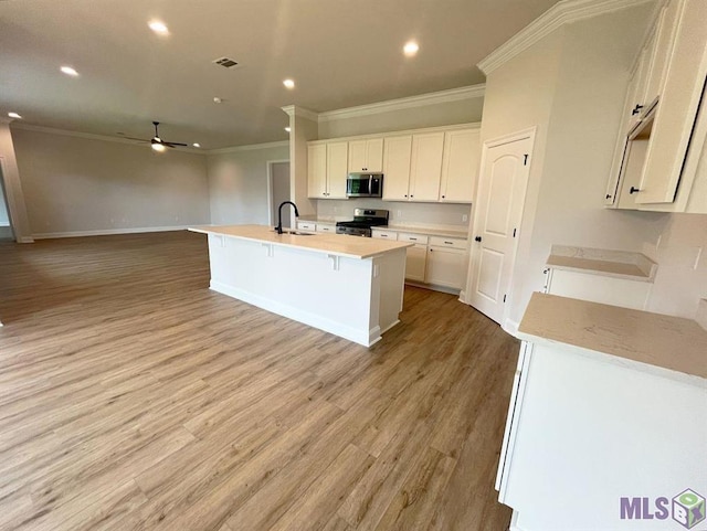 kitchen featuring stainless steel appliances, ornamental molding, a sink, ceiling fan, and open floor plan
