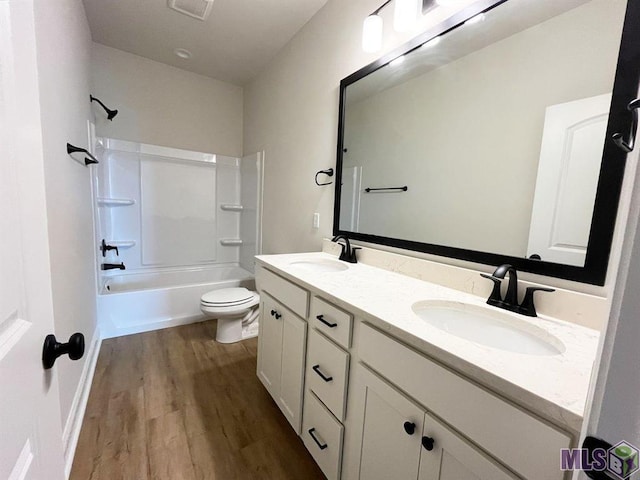 full bath with wood finished floors, toilet, double vanity, and shower / bath combination