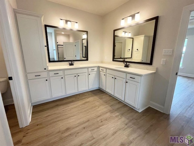 bathroom featuring wood finished floors, baseboards, and double vanity
