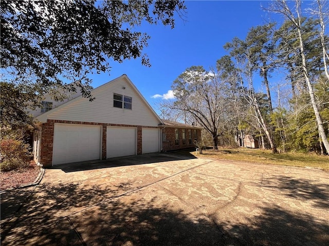 view of home's exterior with a garage, driveway, and brick siding