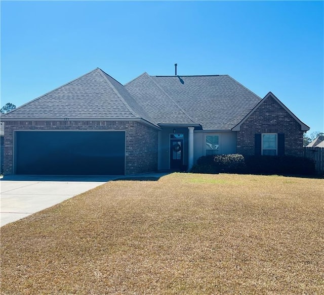 view of front of property featuring an attached garage, brick siding, a shingled roof, concrete driveway, and a front yard