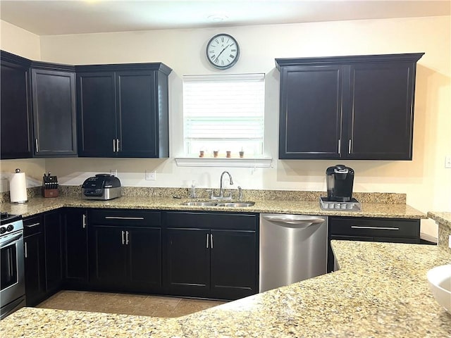 kitchen with a sink, dark cabinetry, dishwasher, and stove