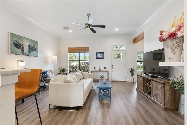 living area with recessed lighting, visible vents, crown molding, and wood finished floors