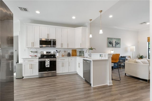 kitchen featuring light wood finished floors, visible vents, appliances with stainless steel finishes, open floor plan, and a peninsula