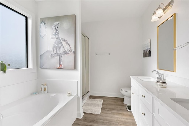 bathroom featuring a garden tub, double vanity, toilet, a sink, and wood finished floors