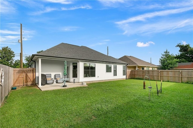 rear view of house with a yard, a shingled roof, a patio area, and a fenced backyard