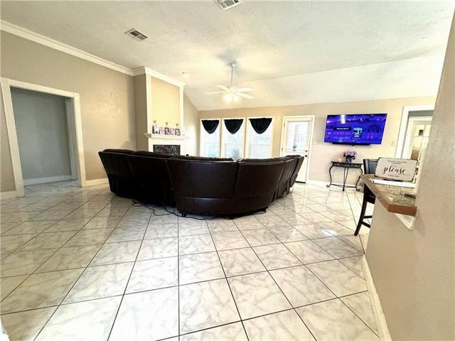 living area featuring ceiling fan, visible vents, vaulted ceiling, and baseboards