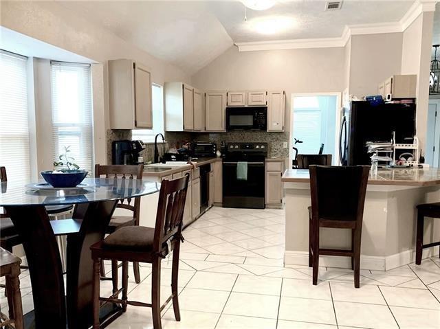 kitchen with a breakfast bar, black appliances, light tile patterned floors, and light countertops