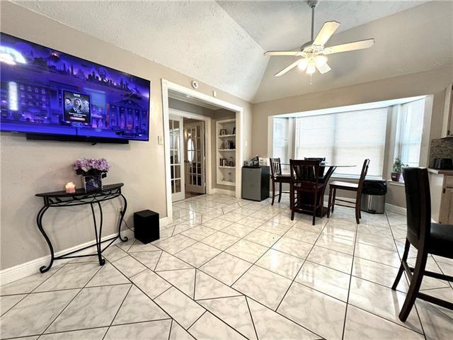 dining space with light tile patterned floors, baseboards, ceiling fan, vaulted ceiling, and a textured ceiling