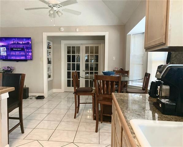 kitchen featuring lofted ceiling, light tile patterned flooring, stone countertops, french doors, and light brown cabinetry