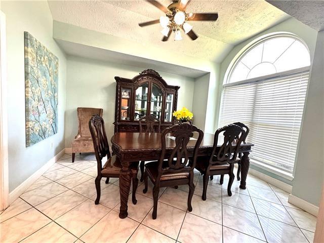 dining room featuring lofted ceiling, light tile patterned floors, a ceiling fan, and a textured ceiling