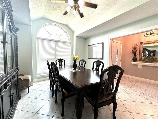 dining room with lofted ceiling, light tile patterned floors, baseboards, and a textured ceiling