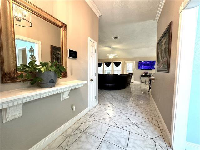 corridor with baseboards, visible vents, and ornamental molding