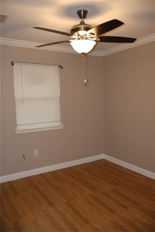 spare room featuring crown molding, baseboards, and wood finished floors