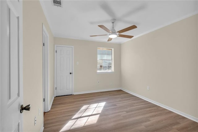 spare room with baseboards, ceiling fan, visible vents, and light wood-style floors