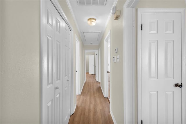 corridor with attic access, baseboards, visible vents, wood finished floors, and crown molding