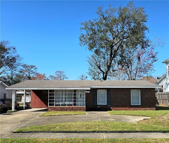 single story home featuring an attached carport, concrete driveway, brick siding, and a front lawn