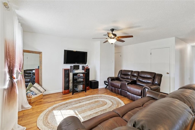 living room with a textured ceiling, ceiling fan, and light wood-type flooring