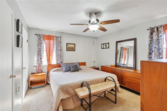 bedroom featuring a textured ceiling, ceiling fan, and light colored carpet