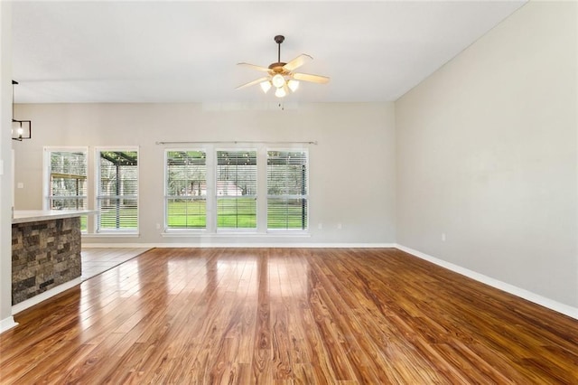 unfurnished living room with ceiling fan, baseboards, and wood finished floors