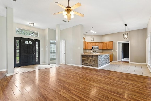 entrance foyer with visible vents, light wood-type flooring, a ceiling fan, and baseboards