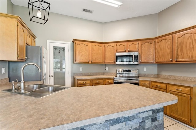 kitchen with hanging light fixtures, appliances with stainless steel finishes, light countertops, and a sink