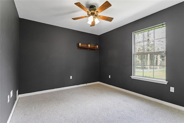 carpeted spare room featuring ceiling fan and baseboards