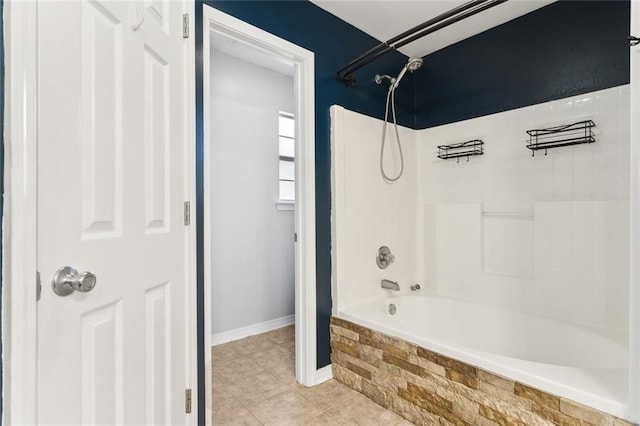 bathroom with washtub / shower combination, tile patterned flooring, and baseboards