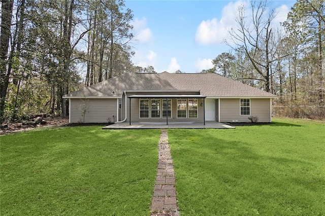 rear view of property featuring a yard, roof with shingles, and a patio