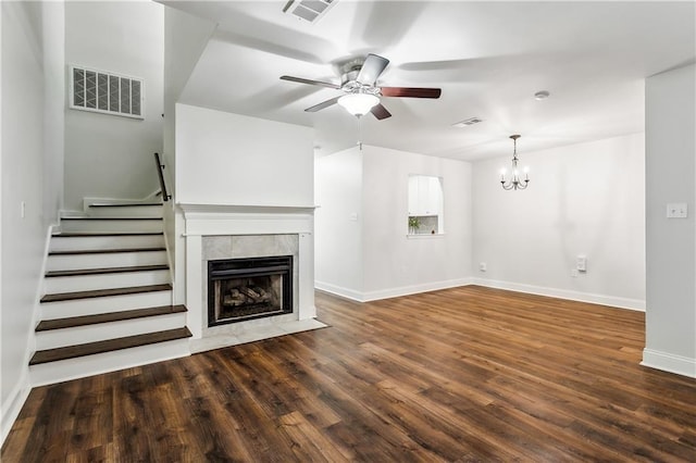 unfurnished living room with baseboards, visible vents, dark wood finished floors, a tiled fireplace, and ceiling fan with notable chandelier