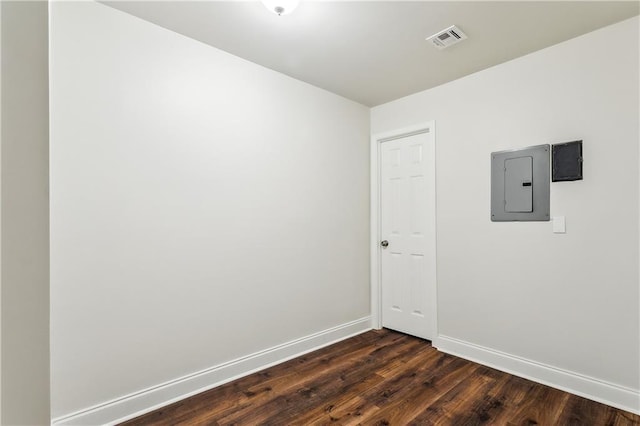 spare room featuring dark wood-type flooring, electric panel, visible vents, and baseboards