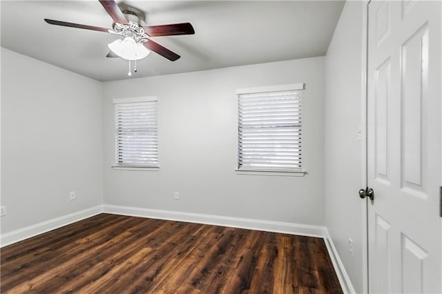 empty room with dark wood-type flooring, baseboards, and a ceiling fan